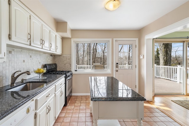 kitchen with a center island, stainless steel gas stove, a sink, white dishwasher, and white cabinetry