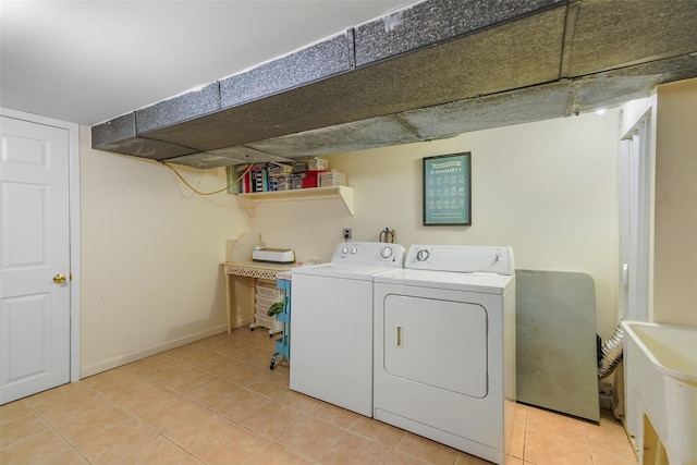 washroom featuring laundry area, baseboards, tile patterned flooring, washer hookup, and a sink