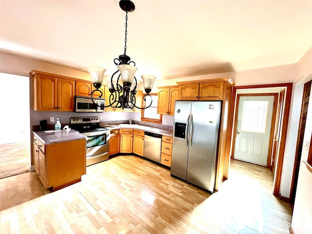 kitchen featuring stainless steel appliances, a wealth of natural light, pendant lighting, and light hardwood / wood-style floors