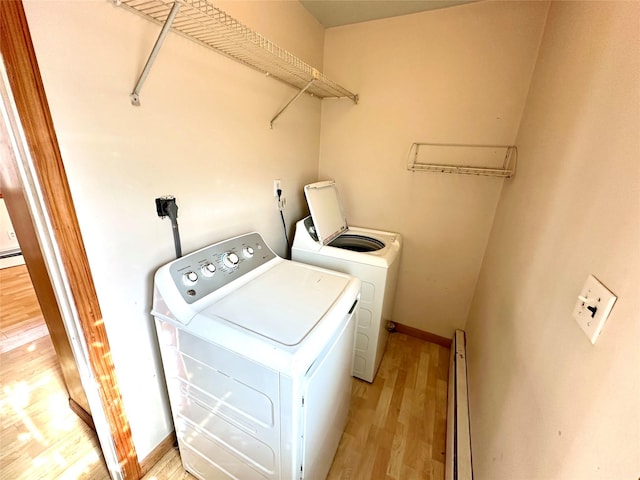 washroom with a baseboard heating unit, washer and clothes dryer, and light wood-type flooring