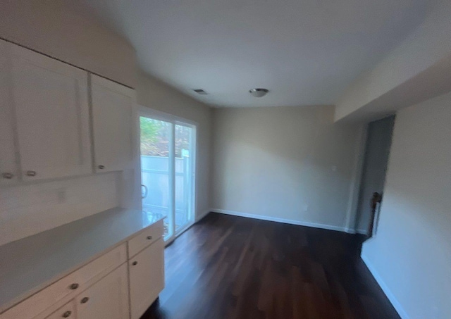 unfurnished dining area with dark wood-type flooring