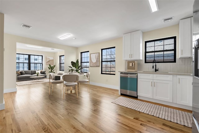 kitchen with dishwasher, sink, white cabinets, and light wood-type flooring