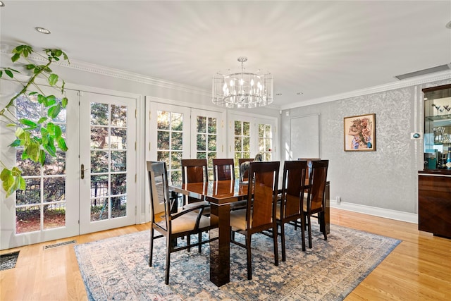 dining space with an inviting chandelier, wood-type flooring, ornamental molding, and french doors