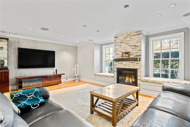 living room with ornamental molding, a stone fireplace, and light hardwood / wood-style flooring