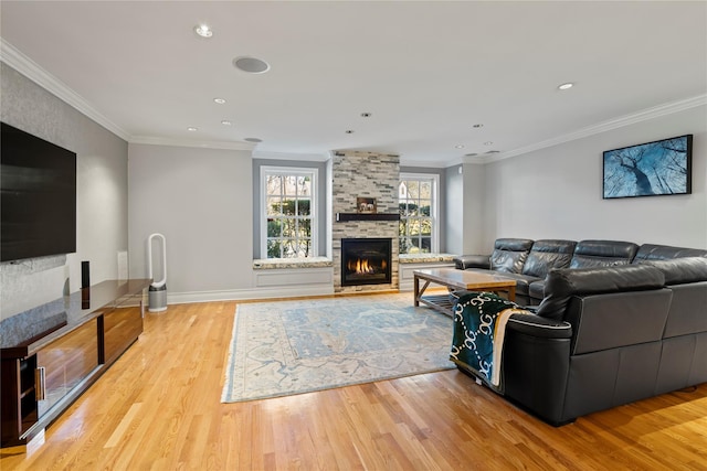 living room featuring ornamental molding, a stone fireplace, and light hardwood / wood-style flooring