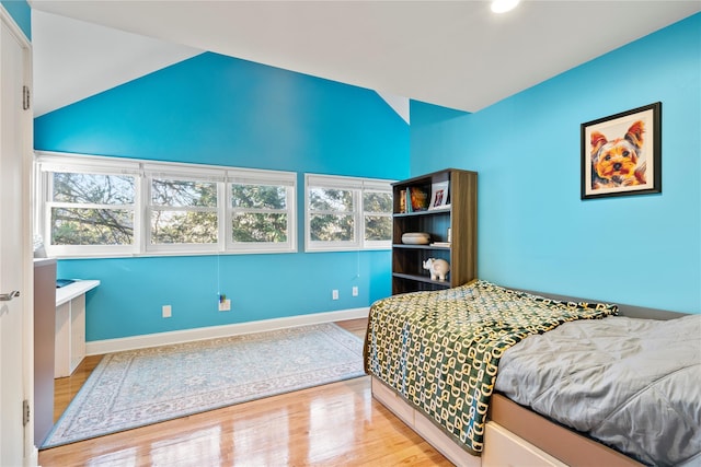 bedroom featuring lofted ceiling, multiple windows, and light wood-type flooring