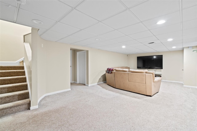 carpeted living room featuring a drop ceiling