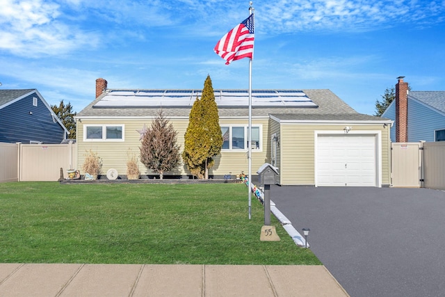 view of front of property featuring a garage, a front yard, and solar panels