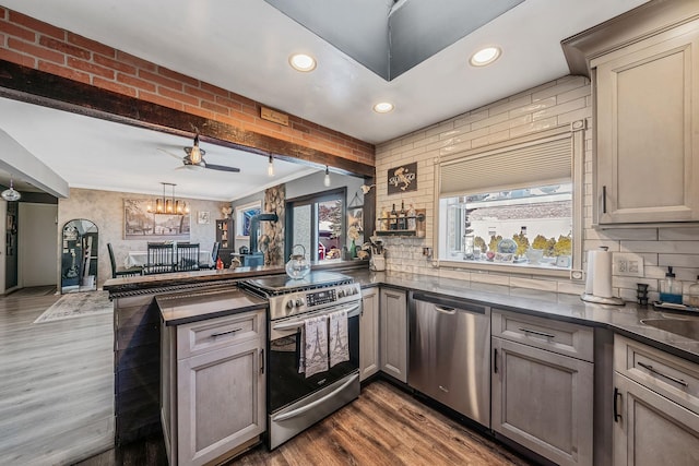 kitchen with dark hardwood / wood-style floors, pendant lighting, decorative backsplash, kitchen peninsula, and stainless steel appliances