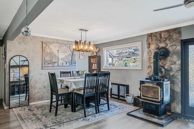 dining space featuring crown molding, ceiling fan, wood-type flooring, and a wood stove