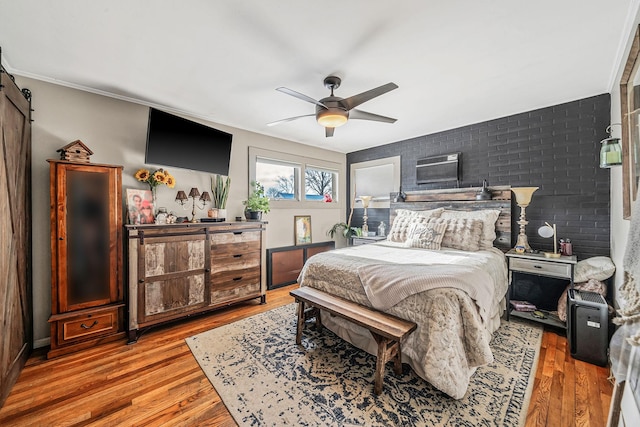 bedroom with ceiling fan, an AC wall unit, a barn door, and light wood-type flooring