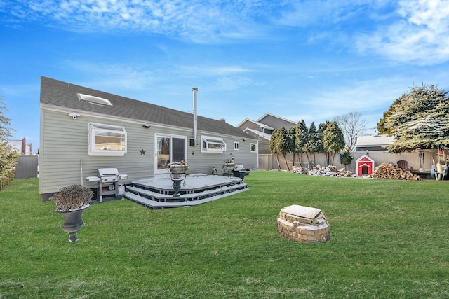 back of property with a wooden deck, a lawn, and an outdoor fire pit