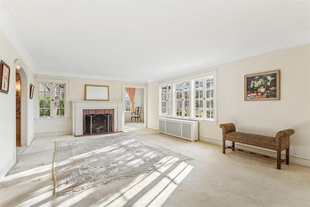 living room with a fireplace, radiator heating unit, and light colored carpet