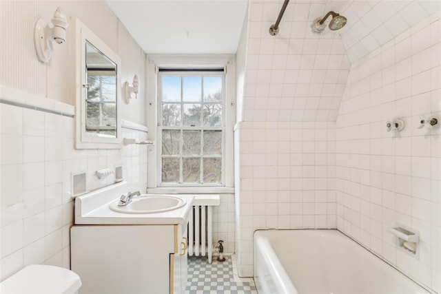 full bathroom featuring tile walls, radiator heating unit, vanity, toilet, and tiled shower / bath