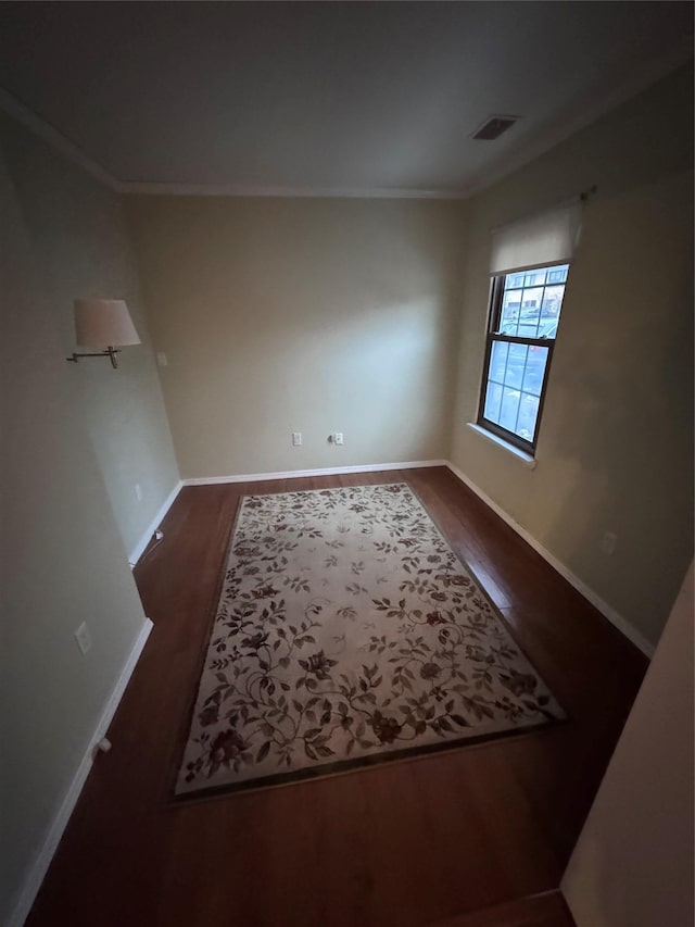 spare room featuring ornamental molding and dark wood-type flooring