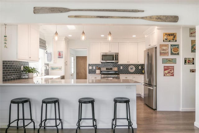 kitchen with sink, white cabinetry, decorative light fixtures, a kitchen breakfast bar, and stainless steel appliances