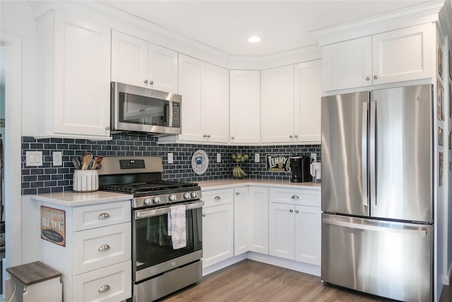 kitchen featuring white cabinetry, appliances with stainless steel finishes, light wood-type flooring, and decorative backsplash