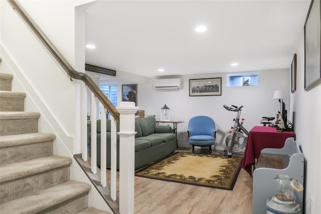 living room with plenty of natural light, a wall mounted air conditioner, and light wood-type flooring