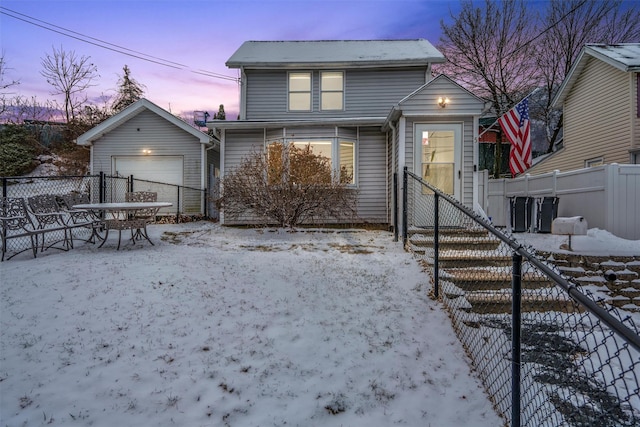 snow covered property with a garage and an outdoor structure