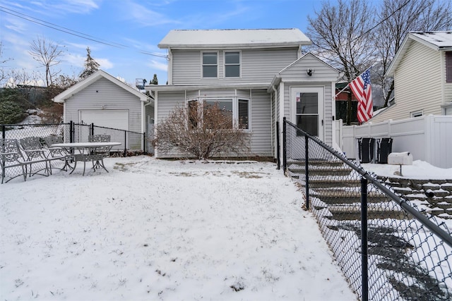 snow covered back of property with an outbuilding and a garage