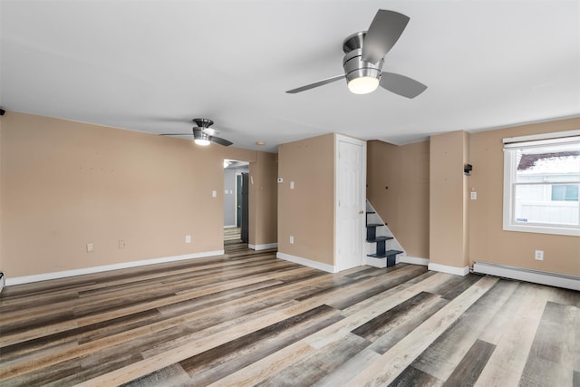 unfurnished living room featuring wood-type flooring, ceiling fan, and baseboard heating