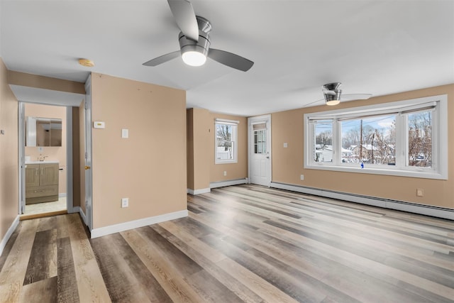 empty room featuring sink, light hardwood / wood-style flooring, and a baseboard heating unit