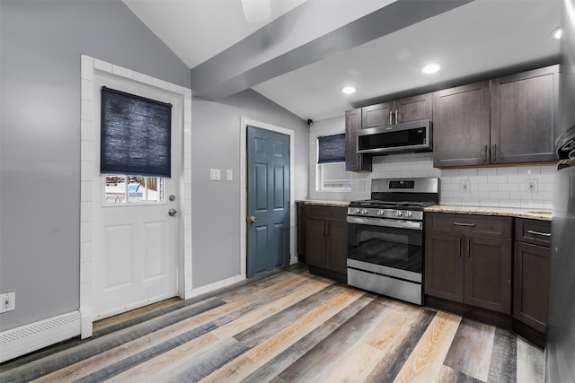 kitchen featuring tasteful backsplash, lofted ceiling, stainless steel appliances, light stone countertops, and dark brown cabinets