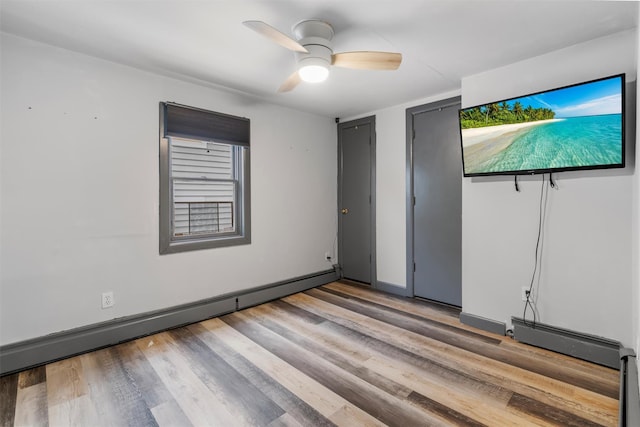 unfurnished bedroom featuring multiple closets, a baseboard heating unit, ceiling fan, and light hardwood / wood-style flooring