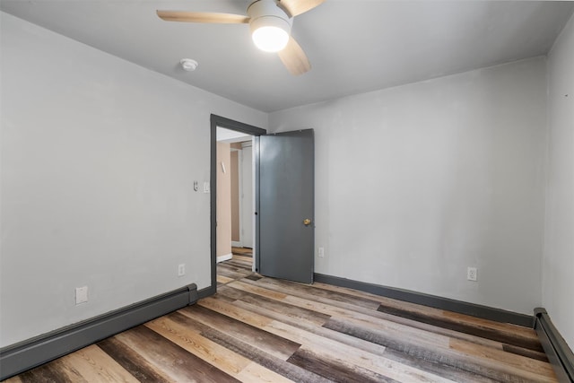 spare room with a baseboard heating unit, light hardwood / wood-style flooring, and ceiling fan