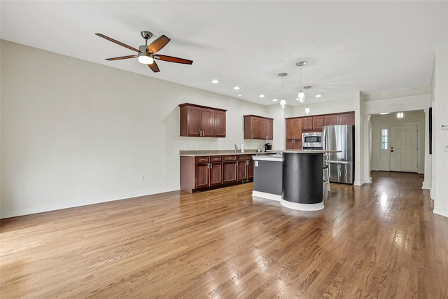 kitchen featuring pendant lighting, stainless steel appliances, a center island, and light wood-type flooring