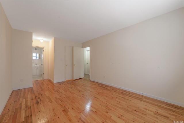 unfurnished bedroom featuring ensuite bath and light hardwood / wood-style floors