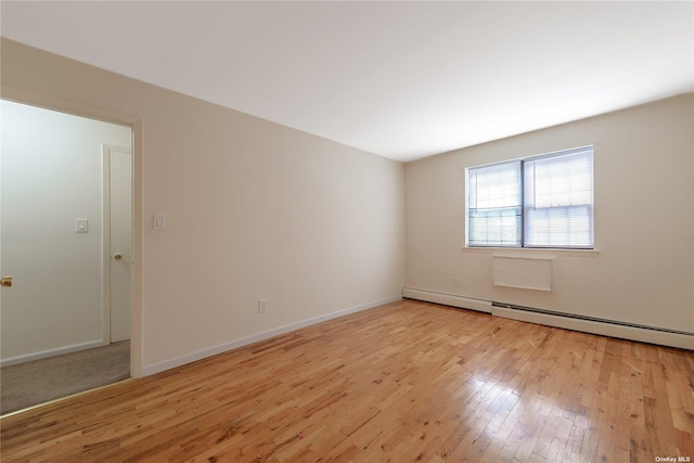 empty room featuring a baseboard radiator and light hardwood / wood-style flooring