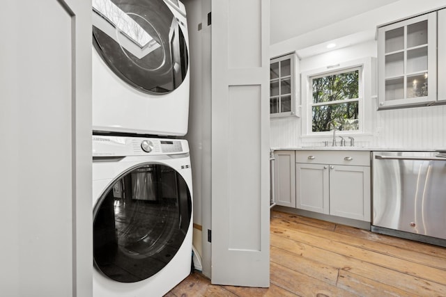 washroom featuring stacked washer and clothes dryer, sink, and light hardwood / wood-style floors