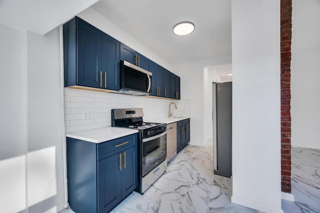 kitchen with appliances with stainless steel finishes, blue cabinetry, sink, and decorative backsplash