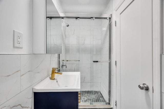 bathroom featuring vanity, a shower with shower door, and tile walls