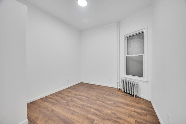 unfurnished room featuring radiator heating unit and hardwood / wood-style floors