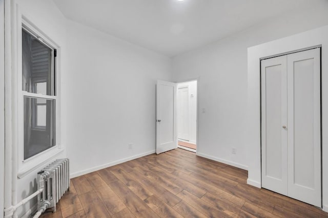 unfurnished bedroom with radiator, dark hardwood / wood-style floors, and a closet