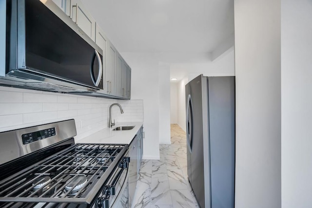 kitchen with tasteful backsplash, sink, gray cabinetry, and appliances with stainless steel finishes