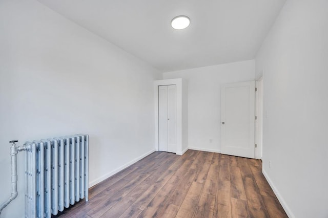 spare room with dark wood-type flooring and radiator