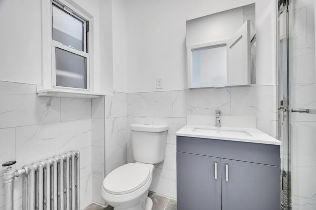 bathroom with vanity, radiator heating unit, tile walls, and toilet