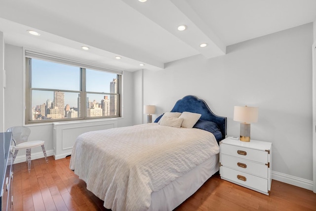 bedroom featuring hardwood / wood-style flooring and beam ceiling