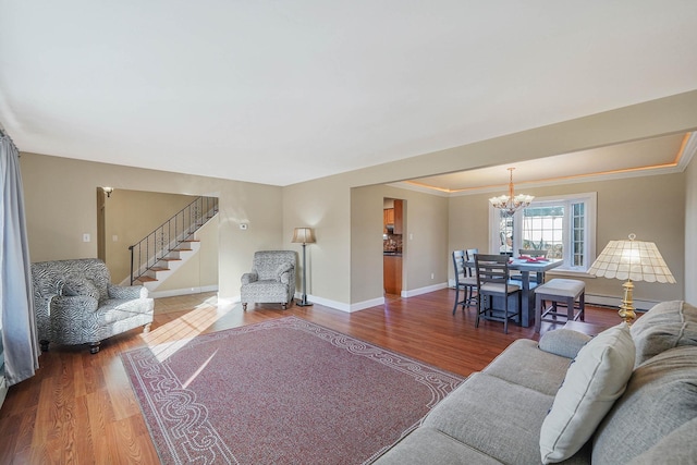 living room with a notable chandelier, crown molding, wood-type flooring, and a baseboard heating unit