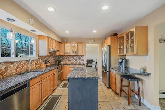 kitchen with a kitchen island, appliances with stainless steel finishes, sink, dark stone countertops, and backsplash