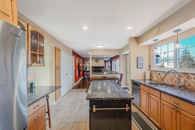 kitchen featuring sink, tasteful backsplash, dark stone counters, a kitchen island, and stainless steel appliances