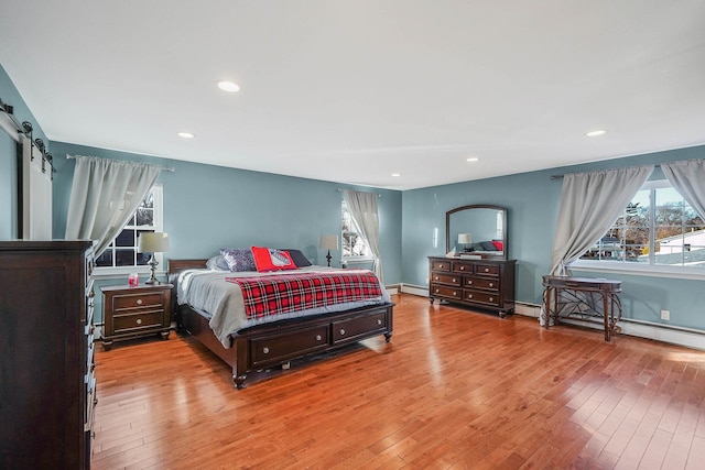 bedroom featuring light hardwood / wood-style flooring, a barn door, and baseboard heating