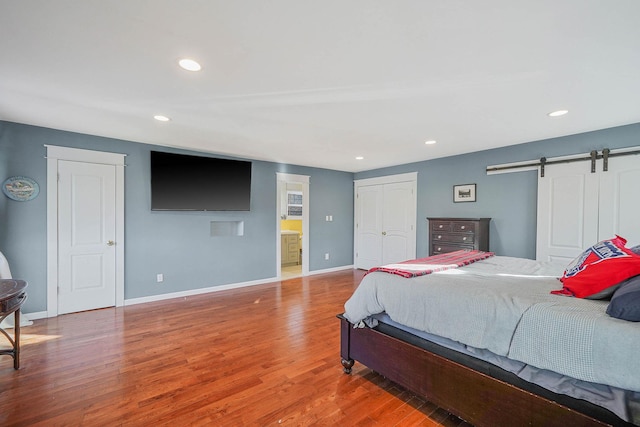 bedroom with hardwood / wood-style flooring, a barn door, and a closet