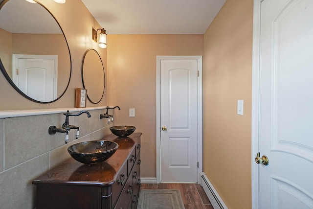 bathroom with wood-type flooring, a baseboard heating unit, and vanity