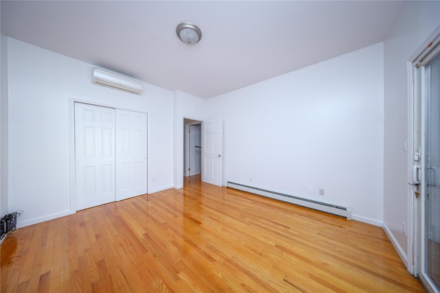 unfurnished bedroom with a baseboard radiator, a closet, a wall unit AC, and light wood-type flooring