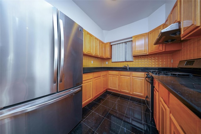 kitchen with sink, stainless steel refrigerator, dark stone countertops, tasteful backsplash, and range with gas stovetop