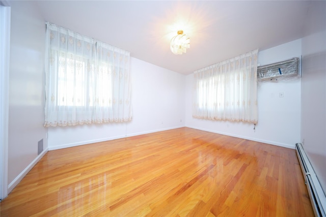 spare room with wood-type flooring and a baseboard heating unit